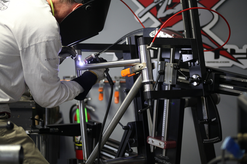 Here I am tacking a frame in my Anvil Super Master frame fixture. The fixture precisely holds frame geometry and sizing. The red hoses convey argon to the inside of the tubes. Known as internal (back) purging, this method is crucial for titanium welding.